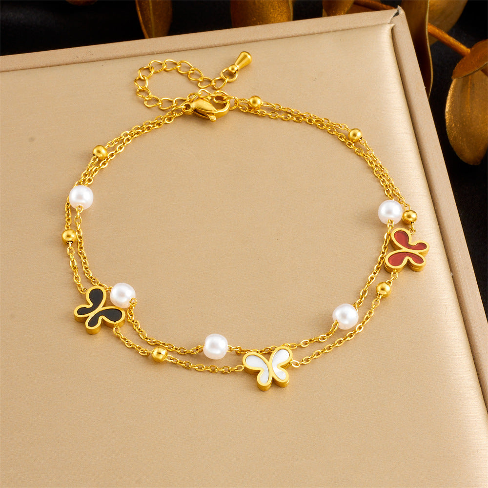 Gold-tone anklet with butterfly charms, red accents, and pearl beads