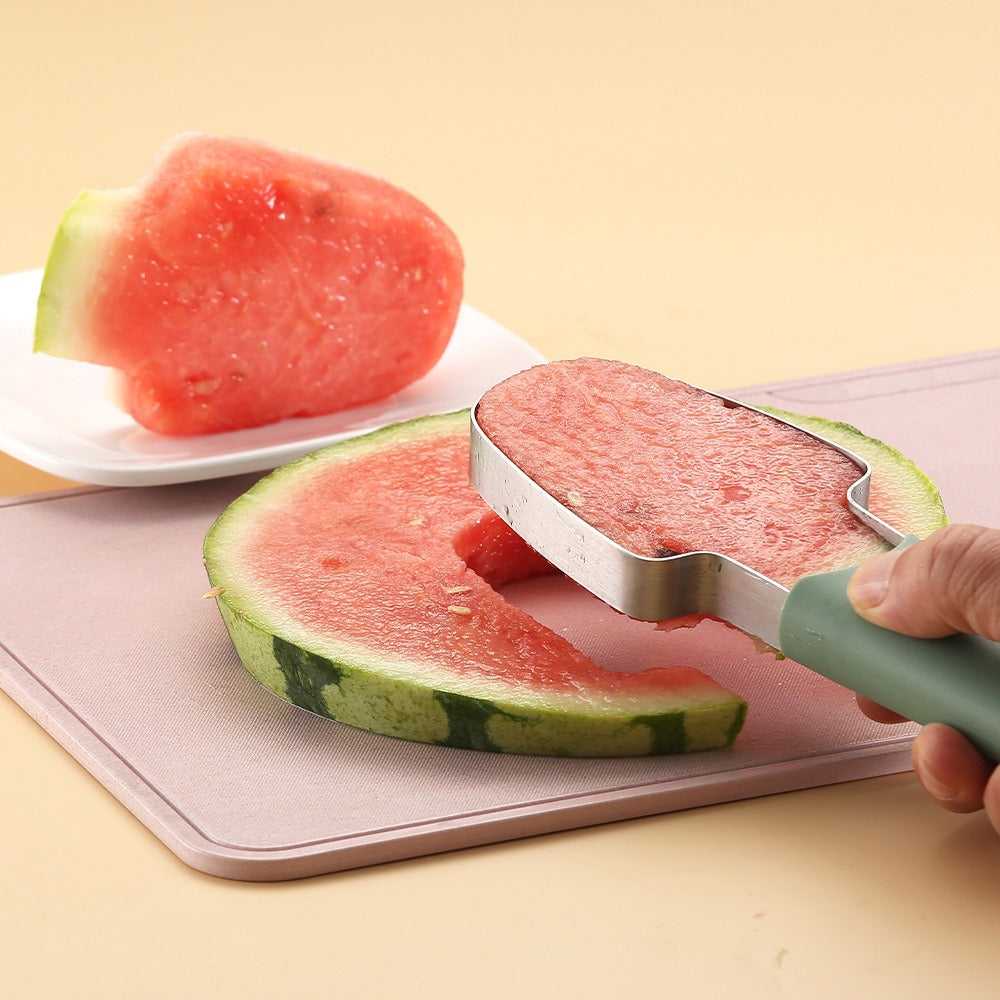 Mint-green handled watermelon cutter tool slicing a watermelon half on a board.