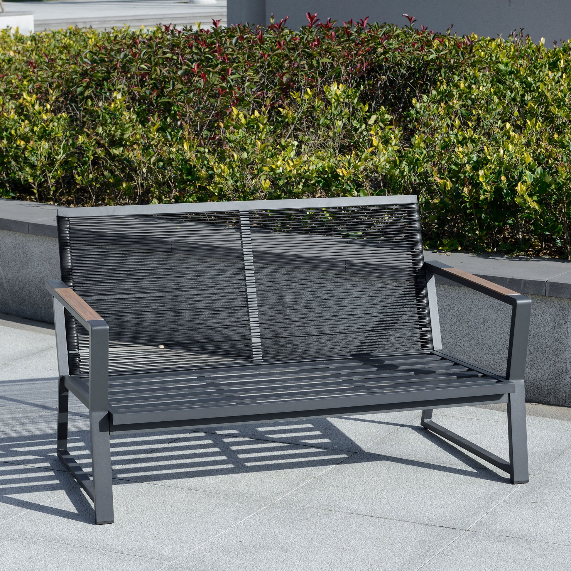 Dark grey patio loveseat with woven backrest, armrests, and thick seat cushions