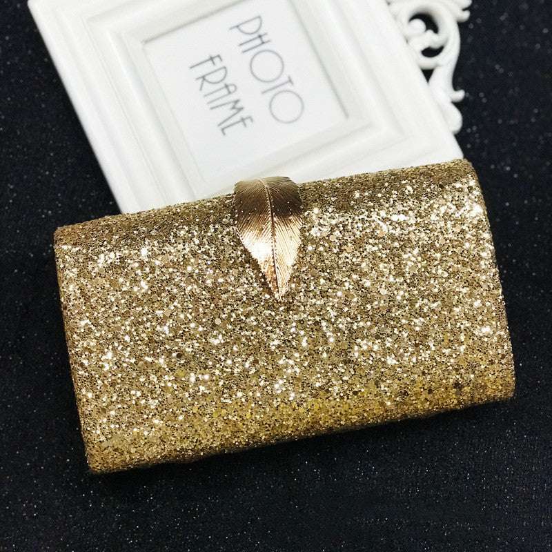 Gold glitter evening bag clutch with leaf-shaped lock at the front