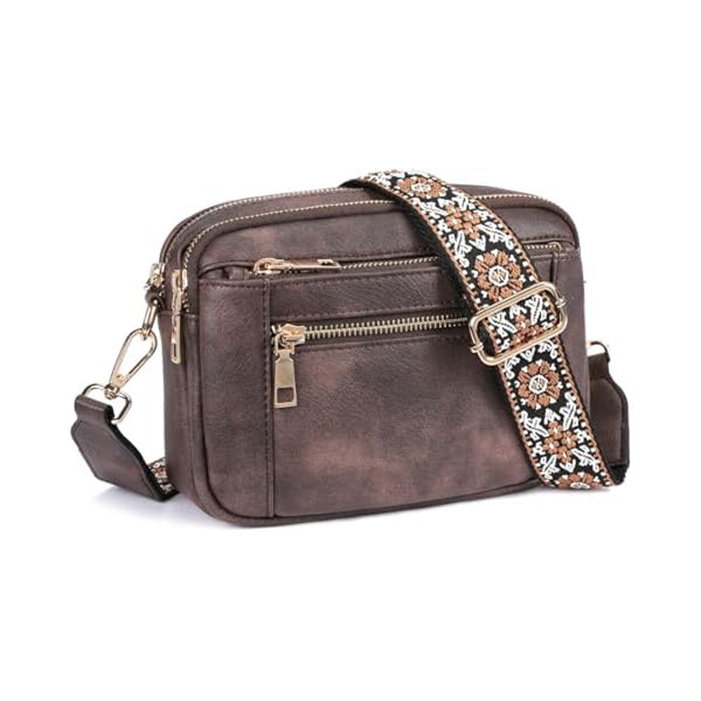 Dark brown crossbody bag with triple zippers and floral patterned shoulder strap.