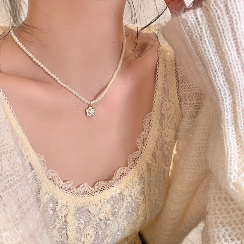 Pearl pendant necklace with small charm at center on a delicate chain