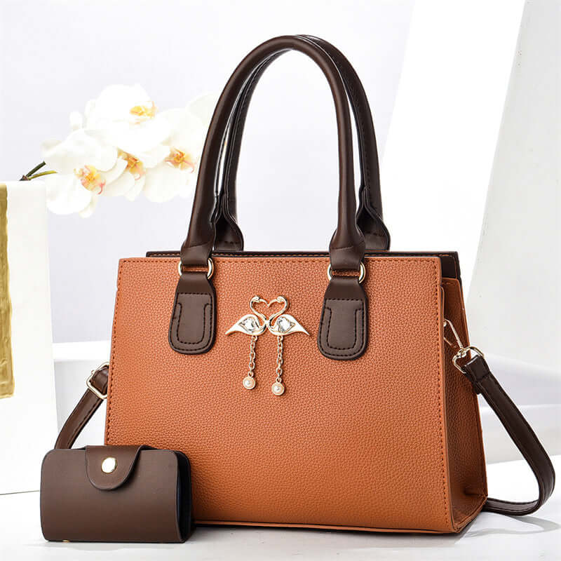 Orange large crossbody tote bag with brown handles, front heart charm, and side pouch
