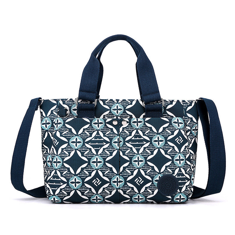 Waterproof shoulder bag in navy with white and teal geometric pattern and navy straps