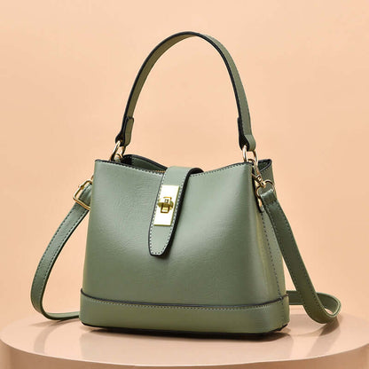 Light green tote handbag with short handles, shoulder strap, and gold clasp