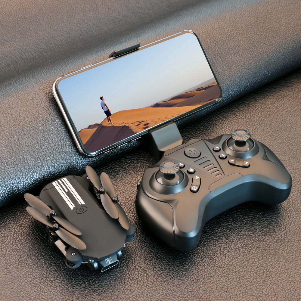 Black drone controller with phone display and a small quadcopter on a leather surface