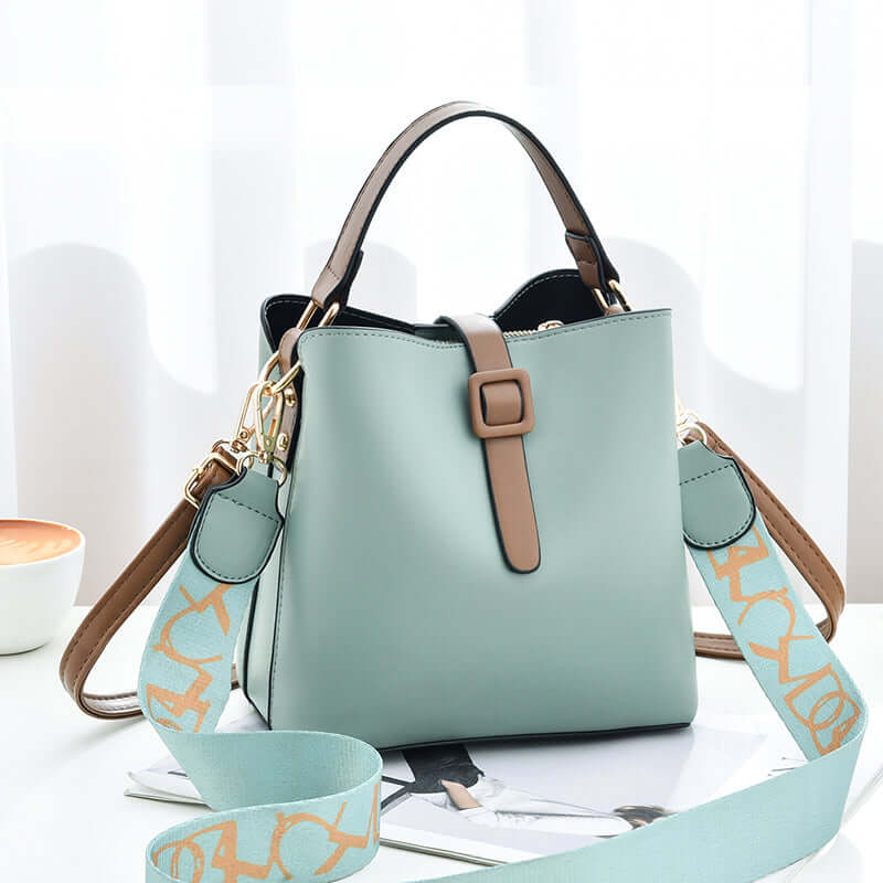Mint PU leather bucket bag with top handles, front buckle tab, and patterned crossbody strap