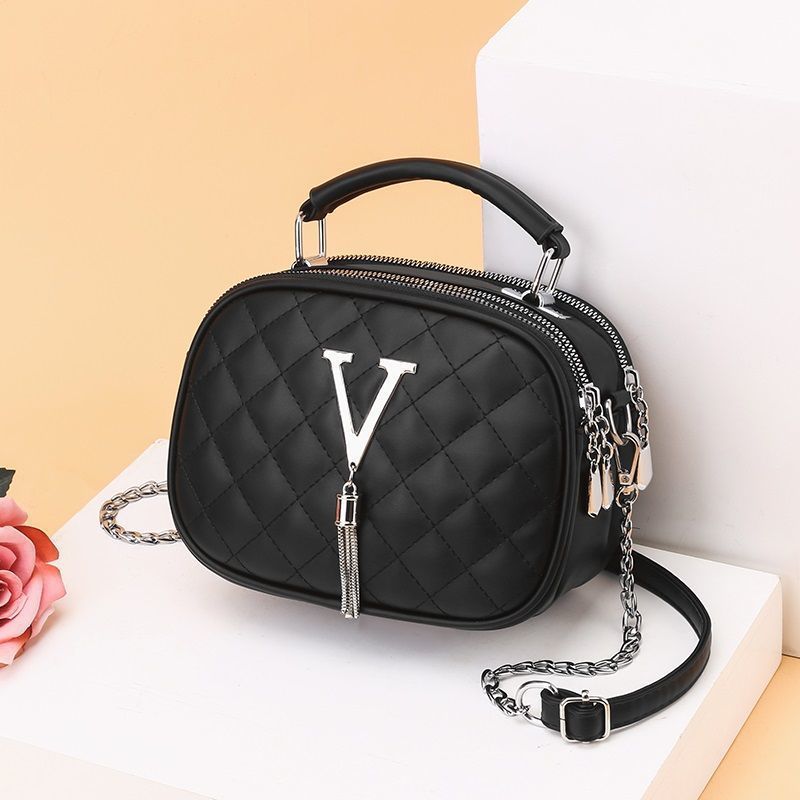Black quilted oval handbag with top handle, chain strap, V emblem and tassel zipper pull