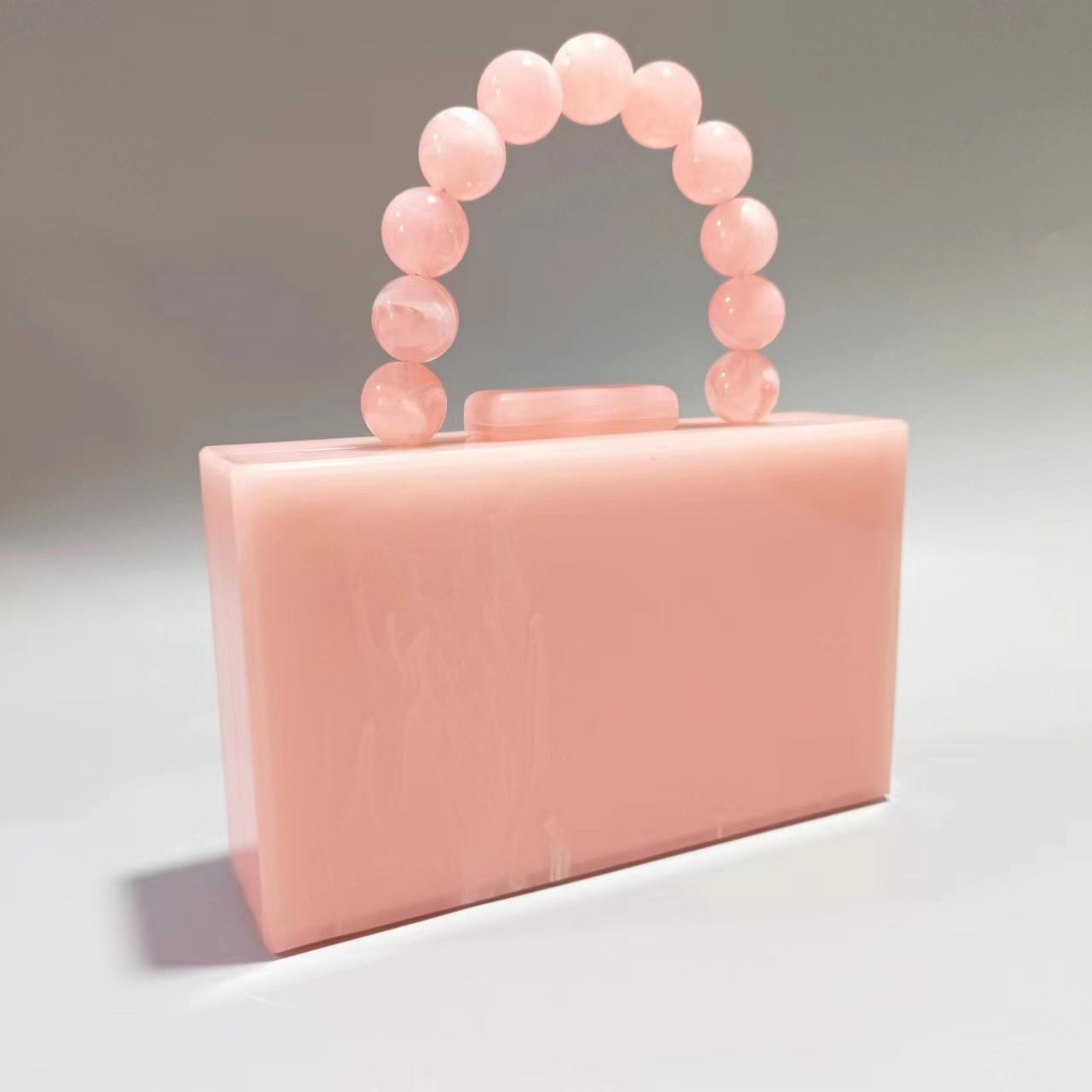 Pink acrylic evening bag with round beaded handle and top bar clasp