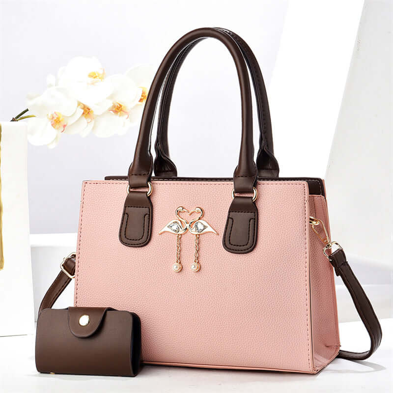 Pink large crossbody tote bag with brown handles, front heart charm, and side pouch