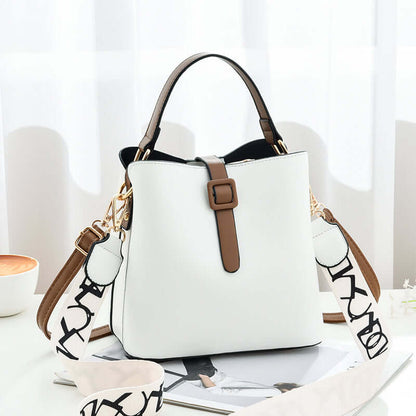 White PU leather bucket bag with top handles, front buckle tab, and logo-pattern strap