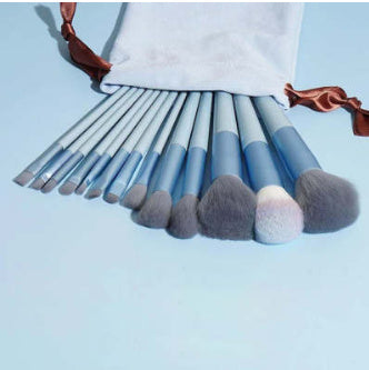 Makeup brush set with blue handles and gray bristles, fanned on white cloth