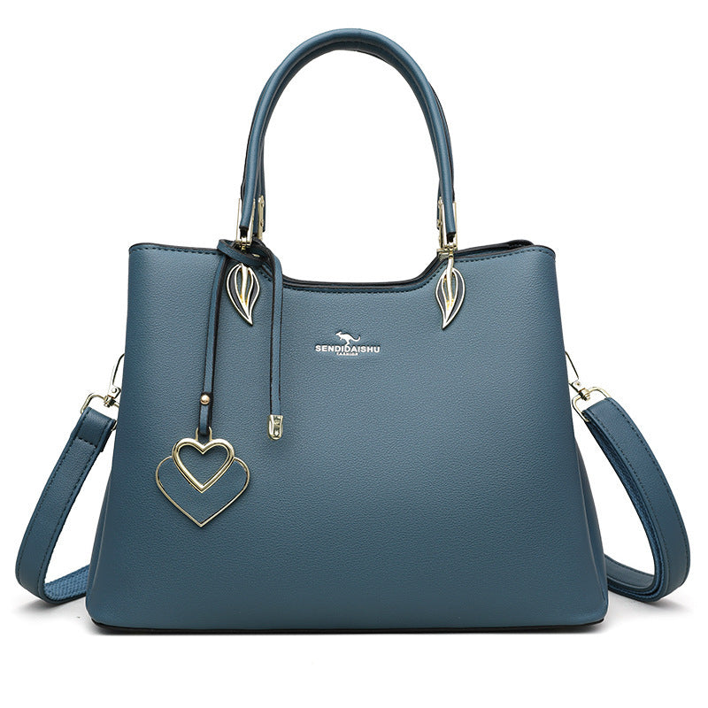 Blue women’s shoulder bag with top handles, heart charm, and gold-tone crossbody strap