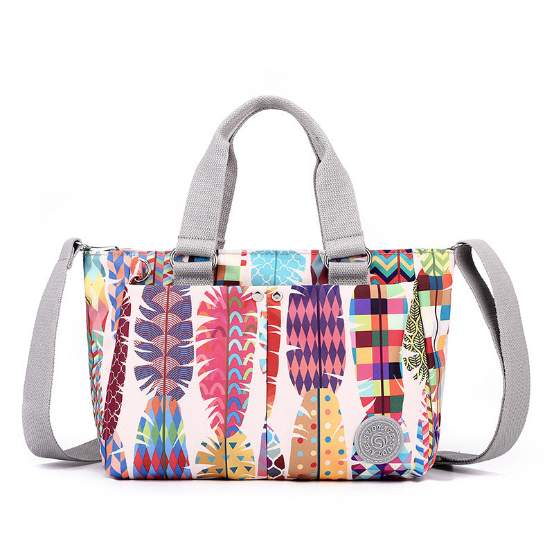 Waterproof shoulder bag with multicolor patchwork print and light gray webbing straps