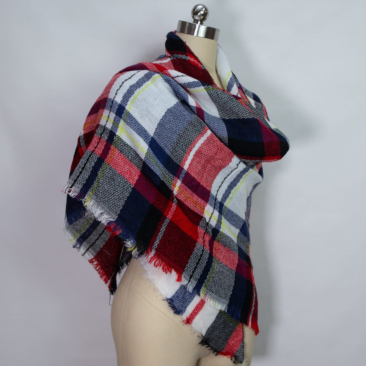Fringed plaid scarf in red, navy, white, and green draped on mannequin