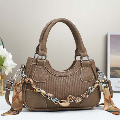 Brown braided chain crossbody handbag with top handles, textured fabric, side tabs.
