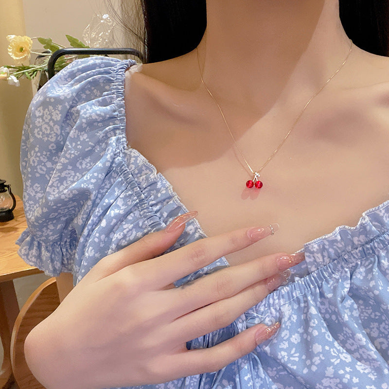 Delicate chain necklace with red cherry-style charm at center