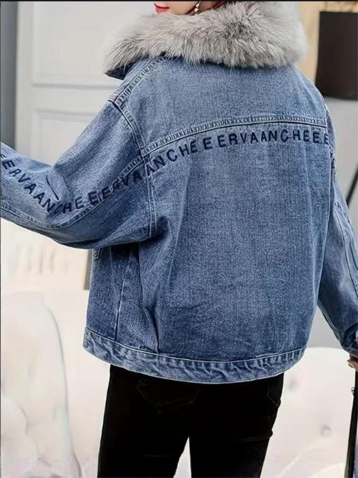 Back view of light blue denim jacket with faux fur collar and long sleeve branding
