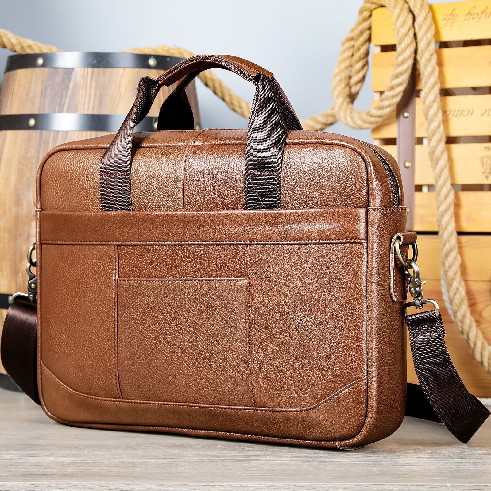 Brown document crossbody bag with top handle, crossbody strap, and zip front pocket