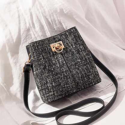 Textured bucket bag with cream front panel and black speckled side, gold clasp, crossbody strap