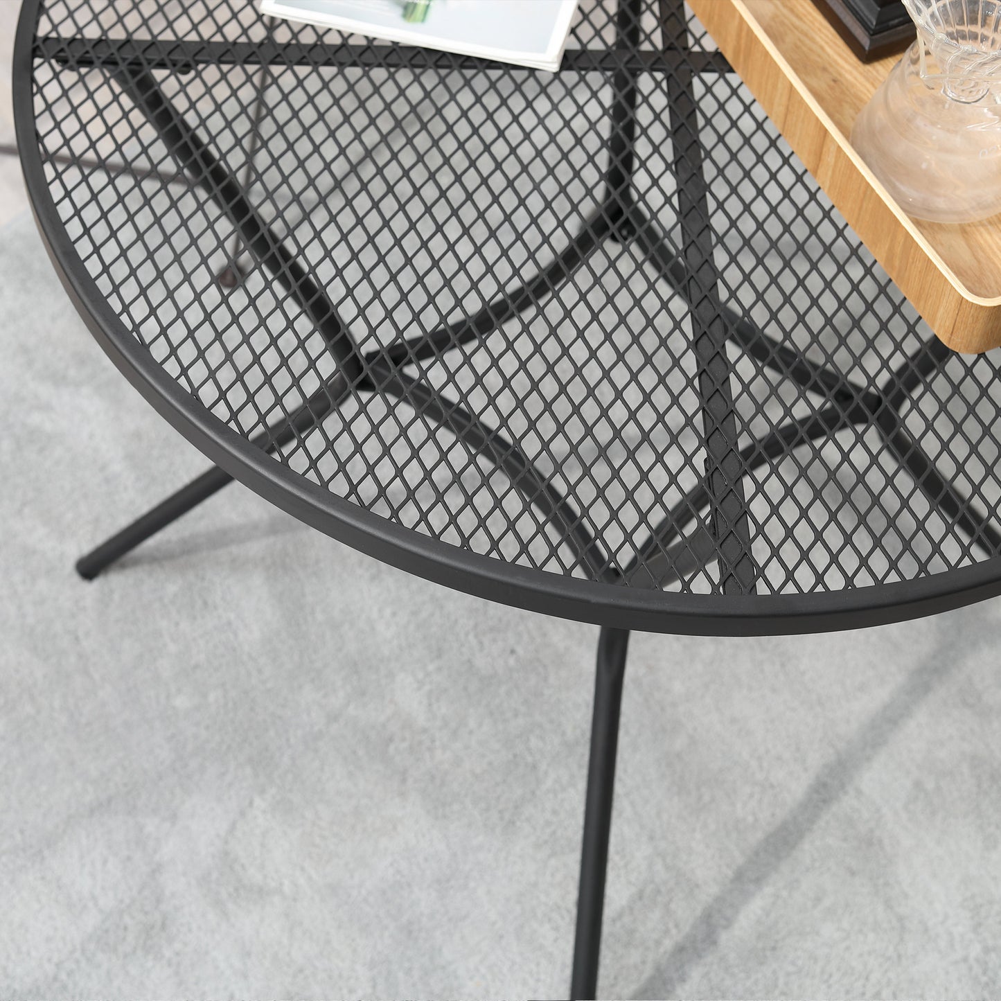 Black metal mesh tabletop rim with curved support legs of a round bistro table