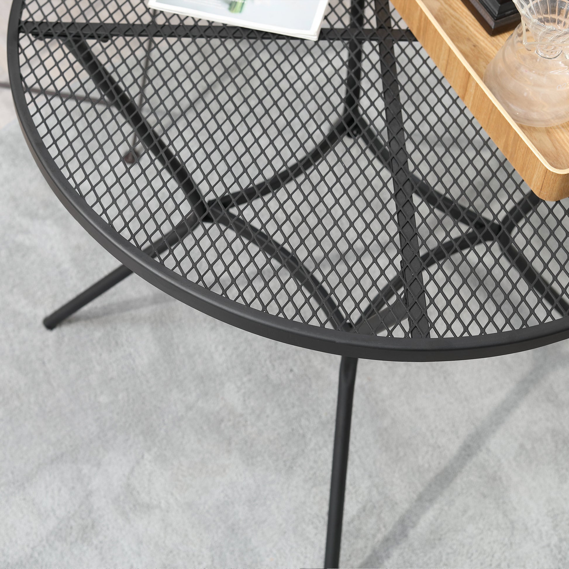 Black metal mesh tabletop rim with curved support legs of a round bistro table