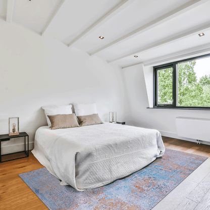 Blue and orange abstract area rug beneath a white bed, rectangular