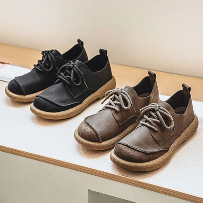 Pair of black and brown shoes on a wooden surface
