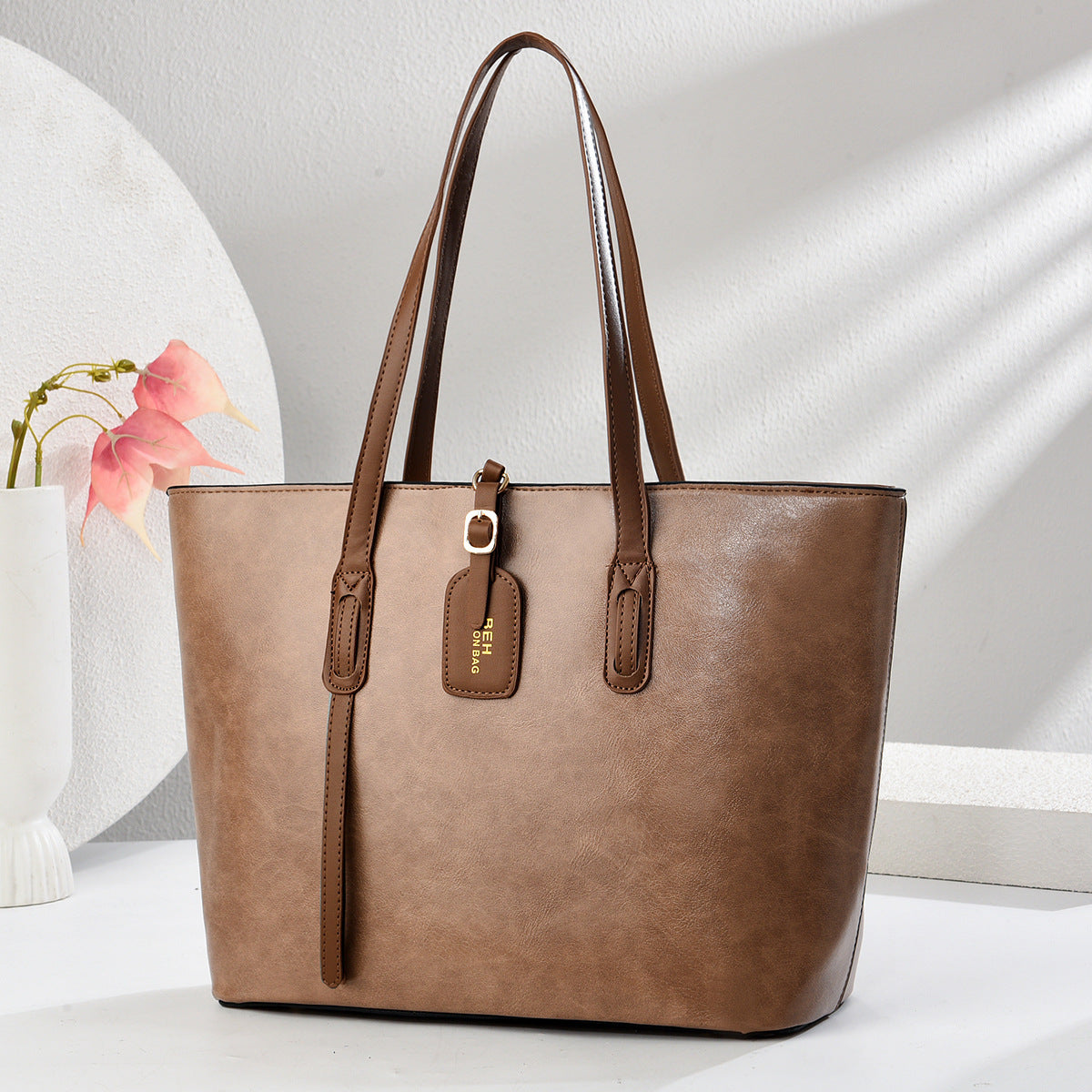 Khaki leather handbag with top handles and front zip pocket with zipper pull tab