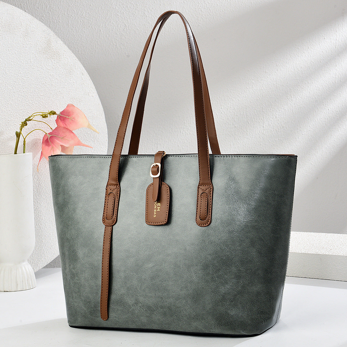 Gray green leather handbag with top handles and front zip pocket with zipper pull tab