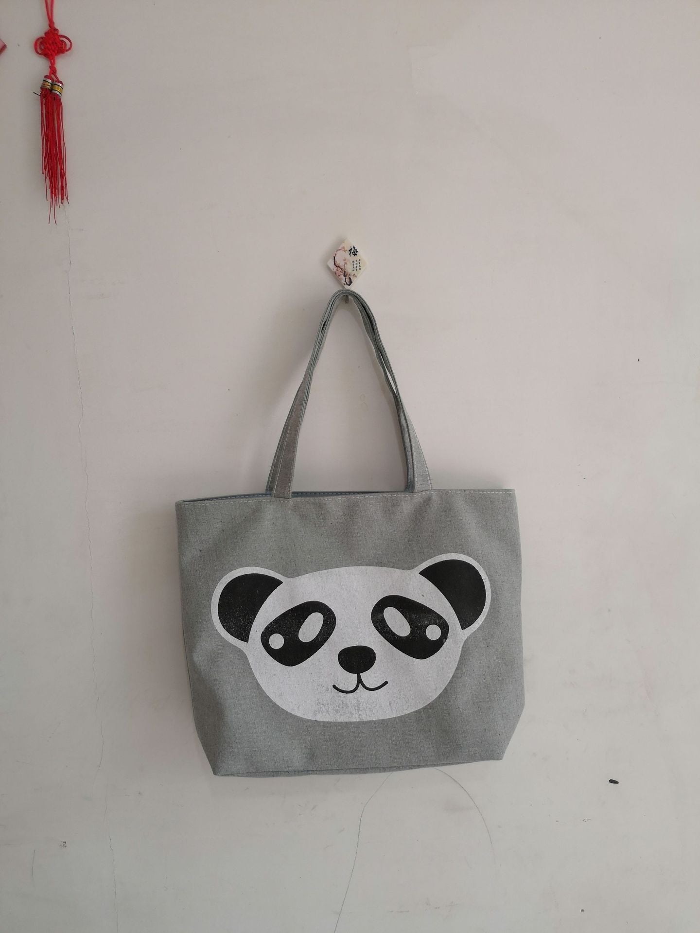 Gray canvas tote bag with large panda face graphic and black-and-white accents, top handle