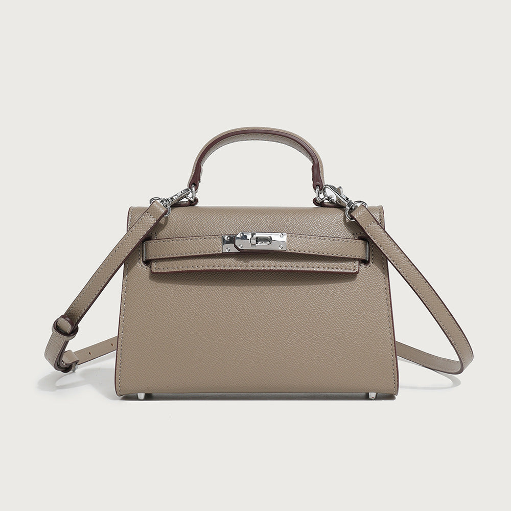 Taupe mini handbag with top handle, flap front, and crossbody strap; metal clasp