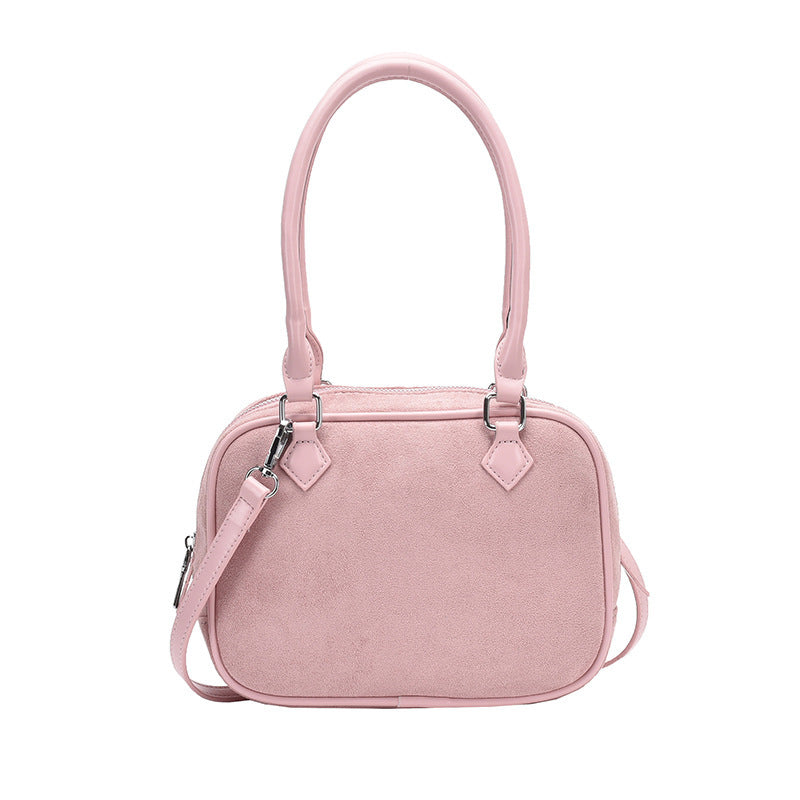Light pink suede crossbody handbag with top handles and adjustable shoulder strap