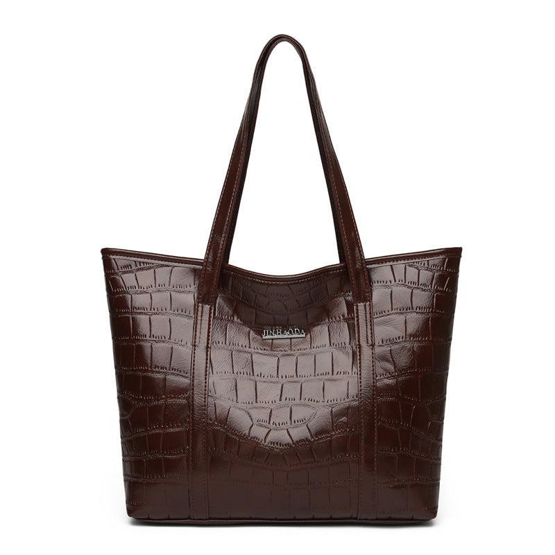 Large brown croc-embossed tote bag with top handles and front logo patch