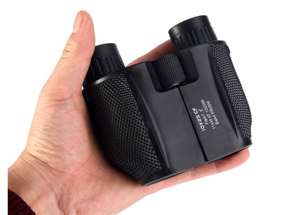 Black binoculars held in a hand on a white background