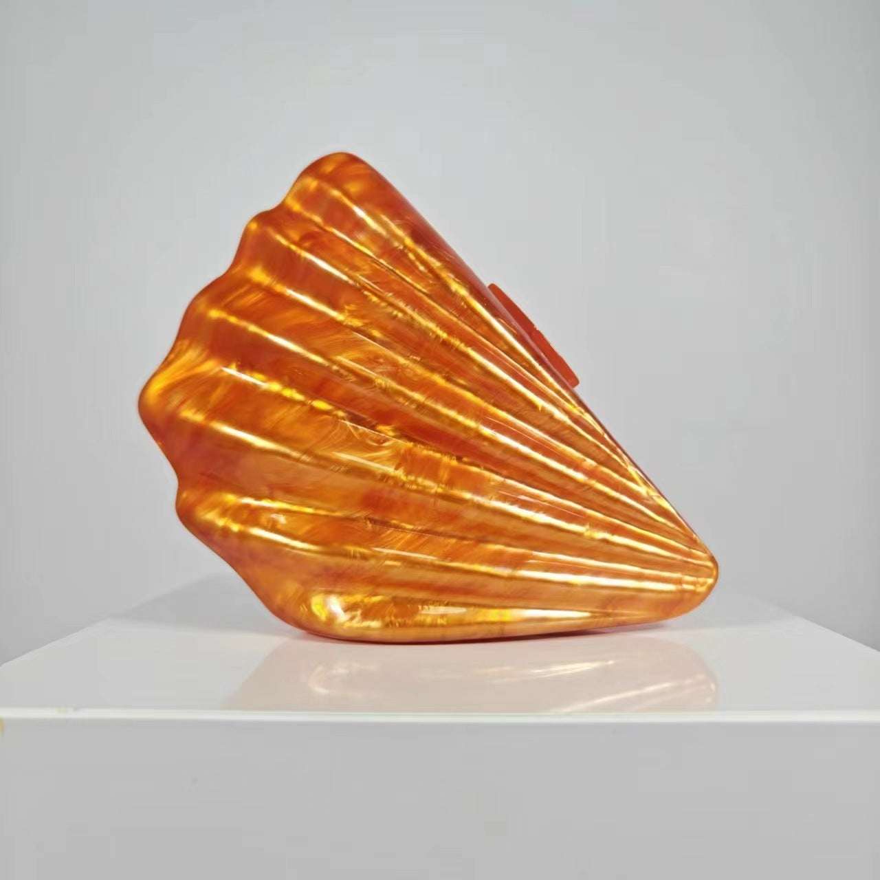 Metallic orange shell crossbody bag with glossy ridged design