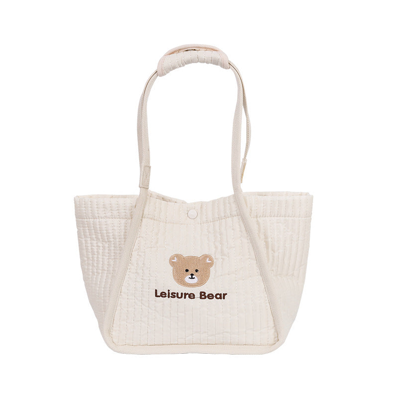Cream quilted mummy bag tote with bear logo on front and loop handles