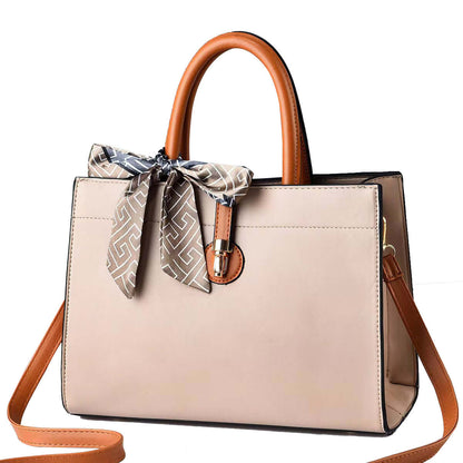 Large beige crossbody tote with brown handles, patterned scarf tie, and metal clasp