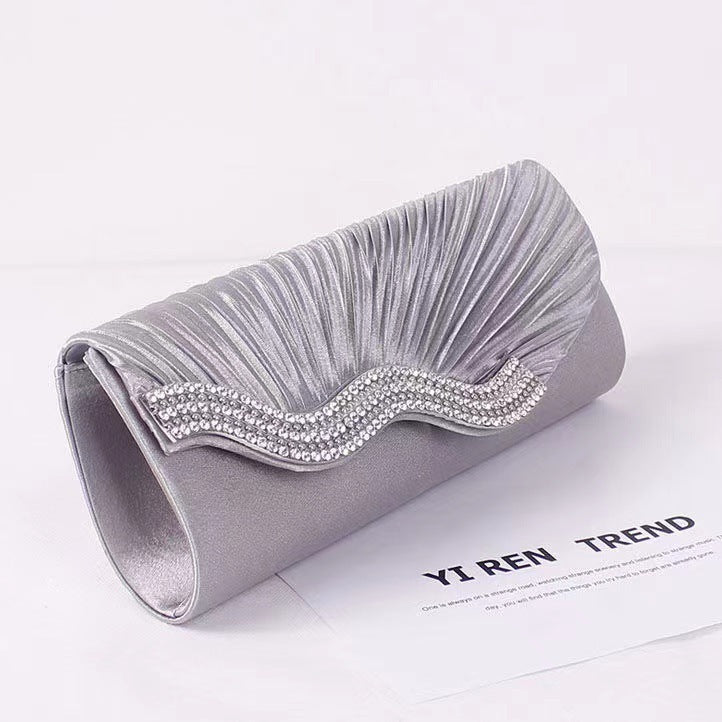 Light gray satin clutch bag with textured ruching and rhinestone wave frame