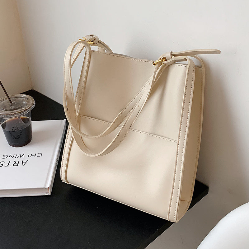 Cream leather shoulder bag with long strap and gold-tone clasp, structured large top