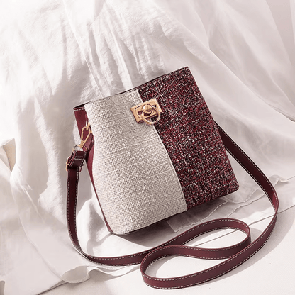 Two-tone textured bucket bag with cream panel and wine speckled side, gold clasp, maroon strap