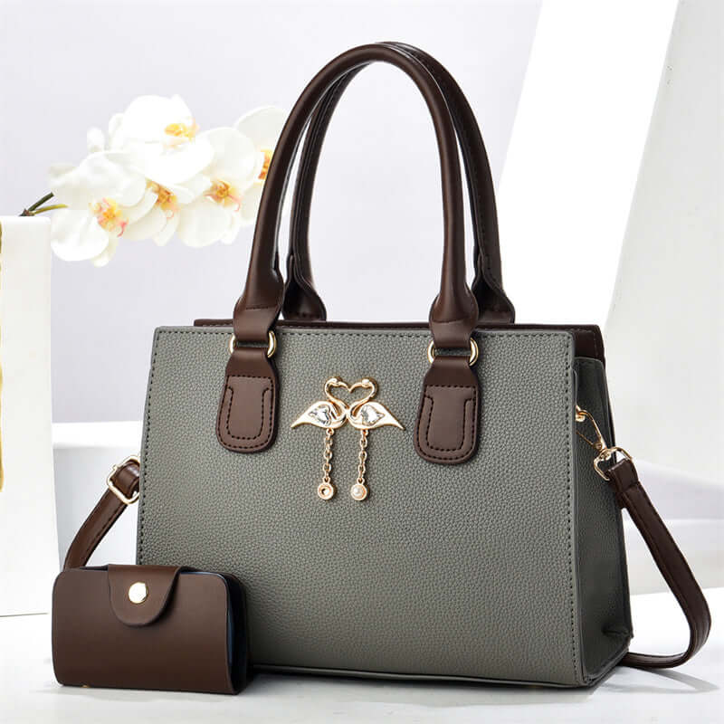 Gray large crossbody tote bag with brown handles, front heart charm, and side pouch