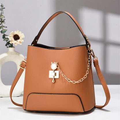 Rust brown PU leather bucket bag with top handle, shoulder strap, and gold chain charm