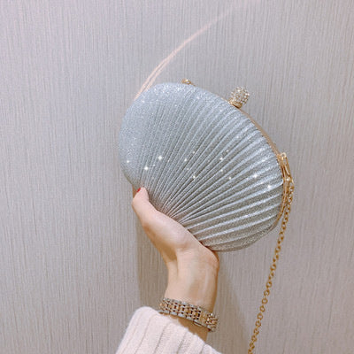 Light blue glitter shell clutch with gold chain and jeweled clasp, held from side