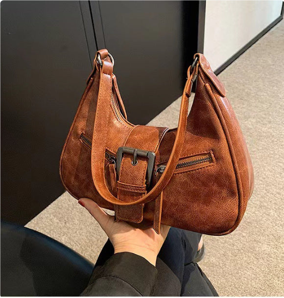Brown one-shoulder underarm bag with front buckle strap and zip pockets