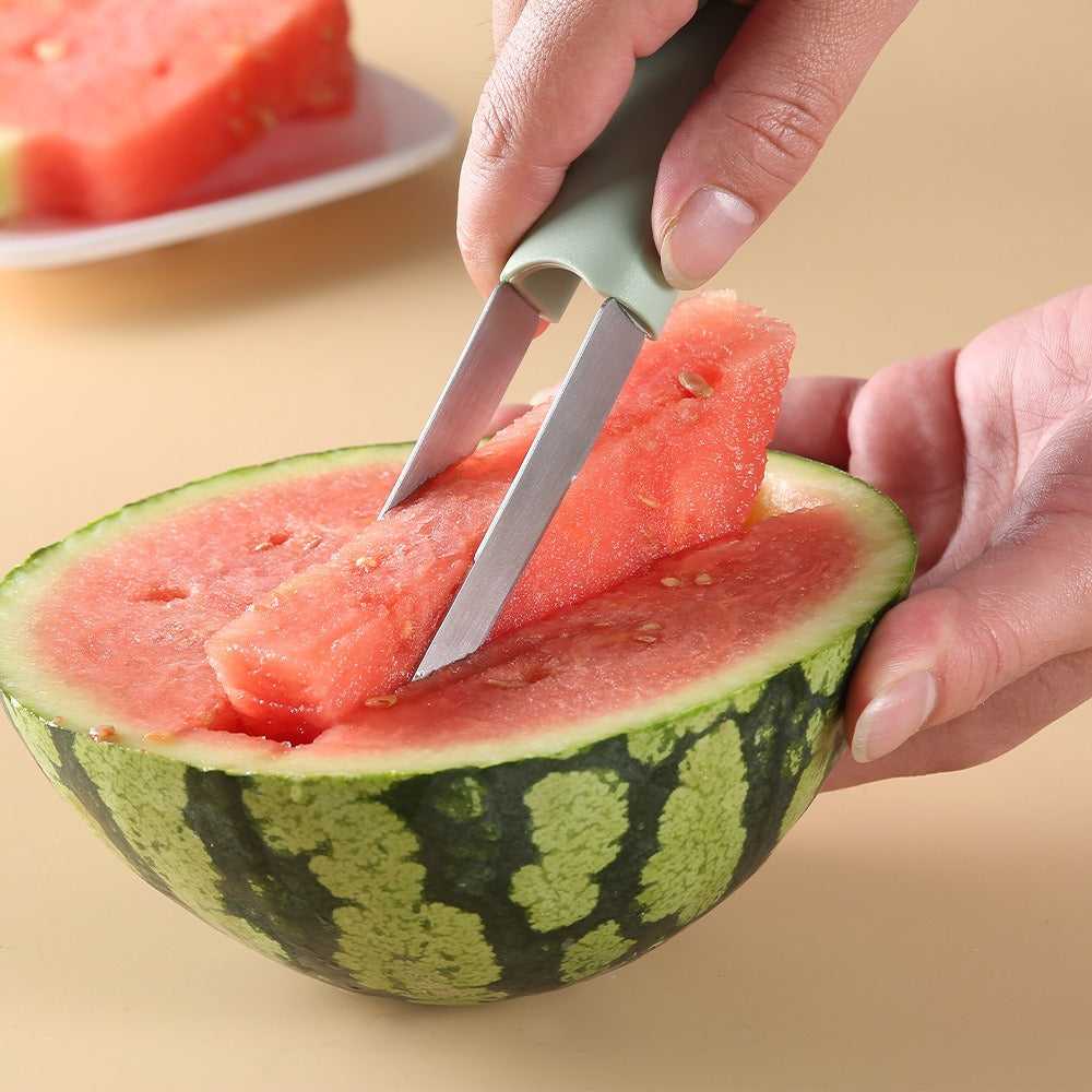 Mint-green watermelon cutter slicing fruit with a stainless blade on a cutting board.