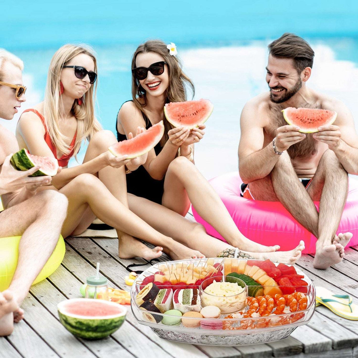 Clear 4-compartment veggie serving tray with mixed produce on a picnic table