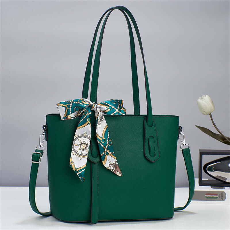Green tote handbag with top handles, front zipper pocket, and multicolor scarf tied at top.