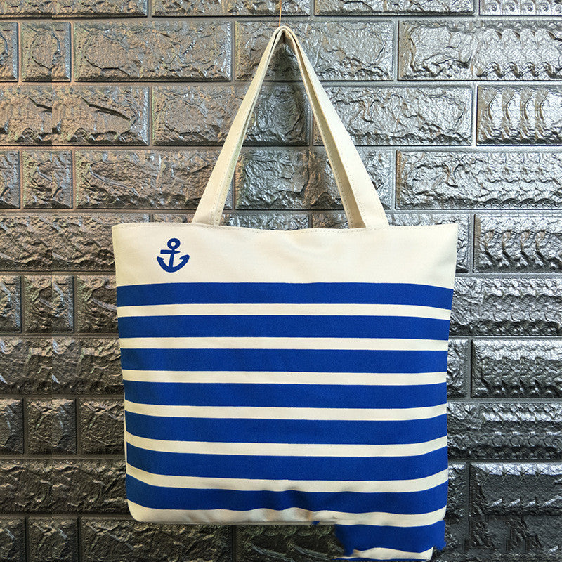White canvas tote bag with blue anchor symbol and wide blue-and-cream stripes