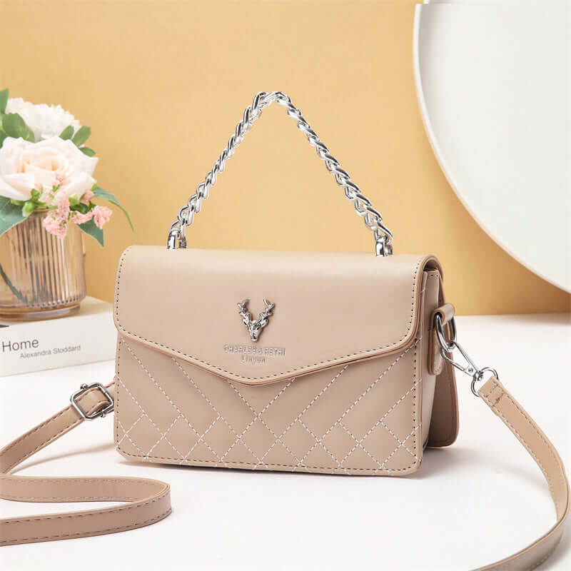 Quilted mini crossbody bag in beige with silver chain strap and front flap with snap.